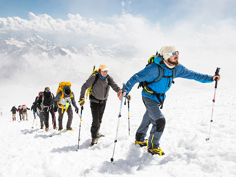Eine Gruppe von Bergsteigern steigt auf den Gipfel eines schneebedeckten Berges.