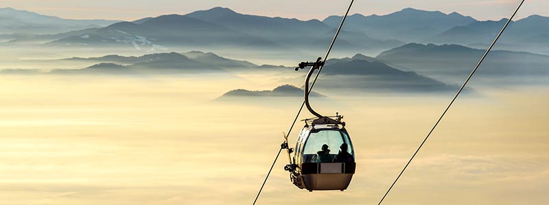 PopUp-Bild-06 Blick auf eine Seilbahn über ein nebeliges Tal.
